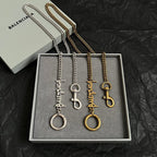 Balenciaga keychain set with silver and gold tone logo charms in gift box