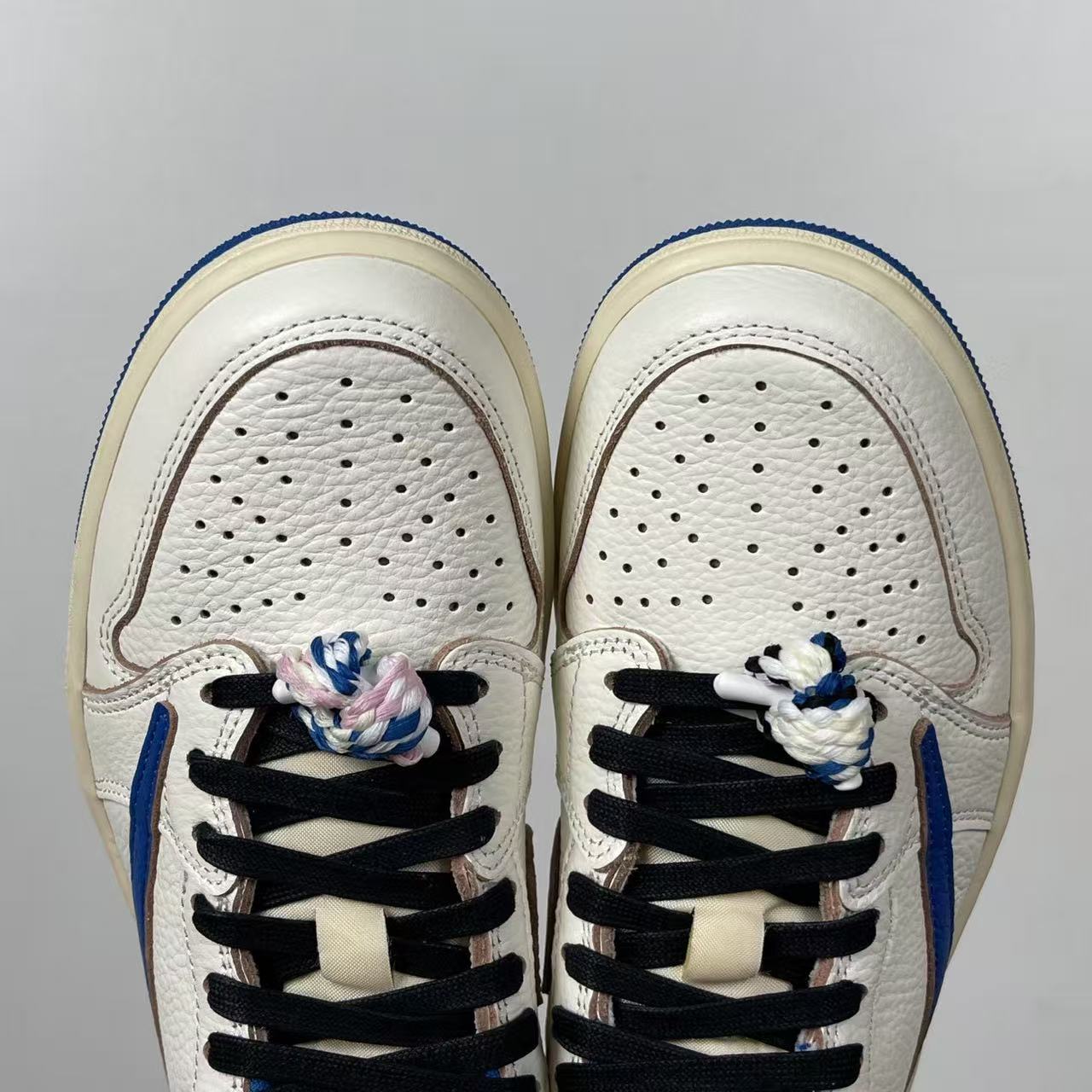 Front view of white sneakers with perforated toe box and black lace system