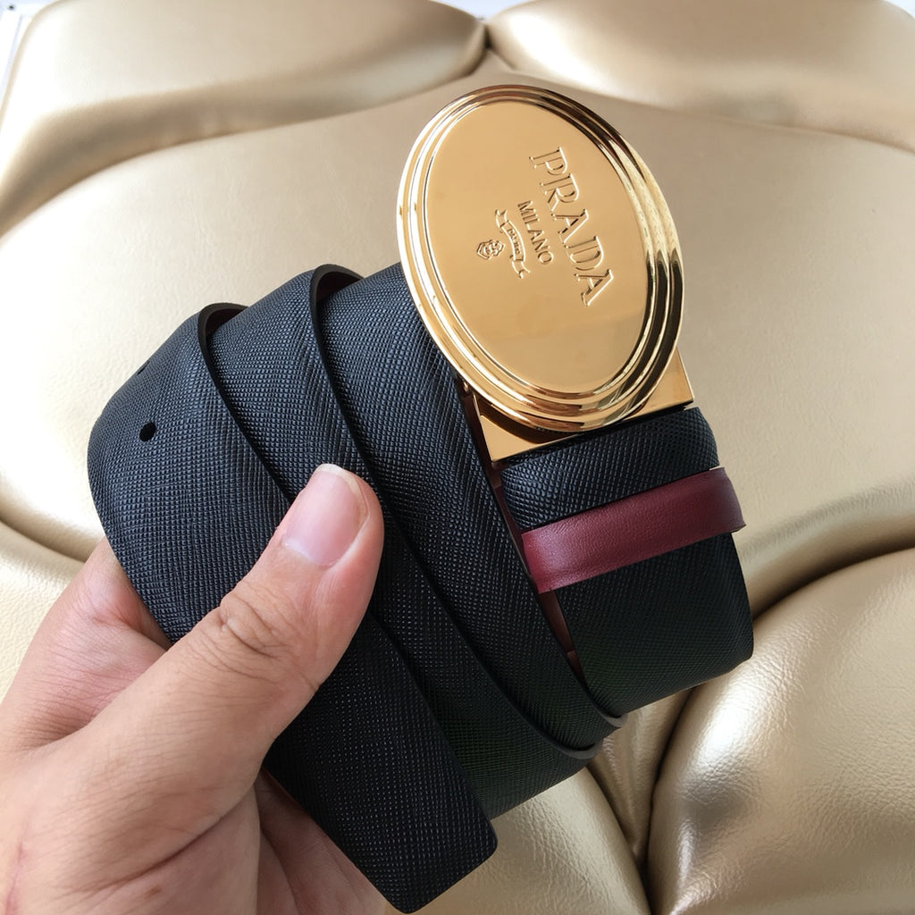 Designer belt with navy strap and burgundy accent, showing oval gold buckle