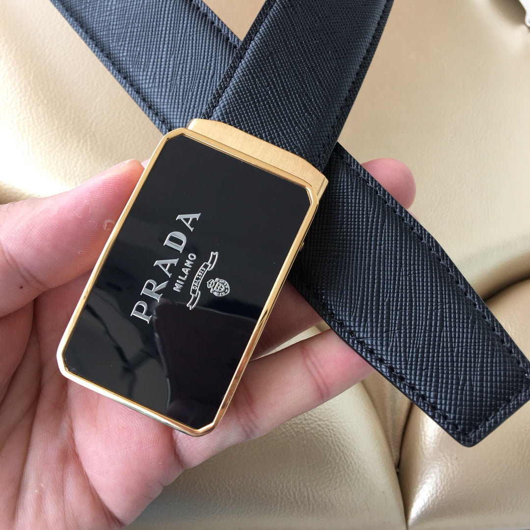 Prada belt buckle close-up in hand, dark plate with Prada logo and gold frame