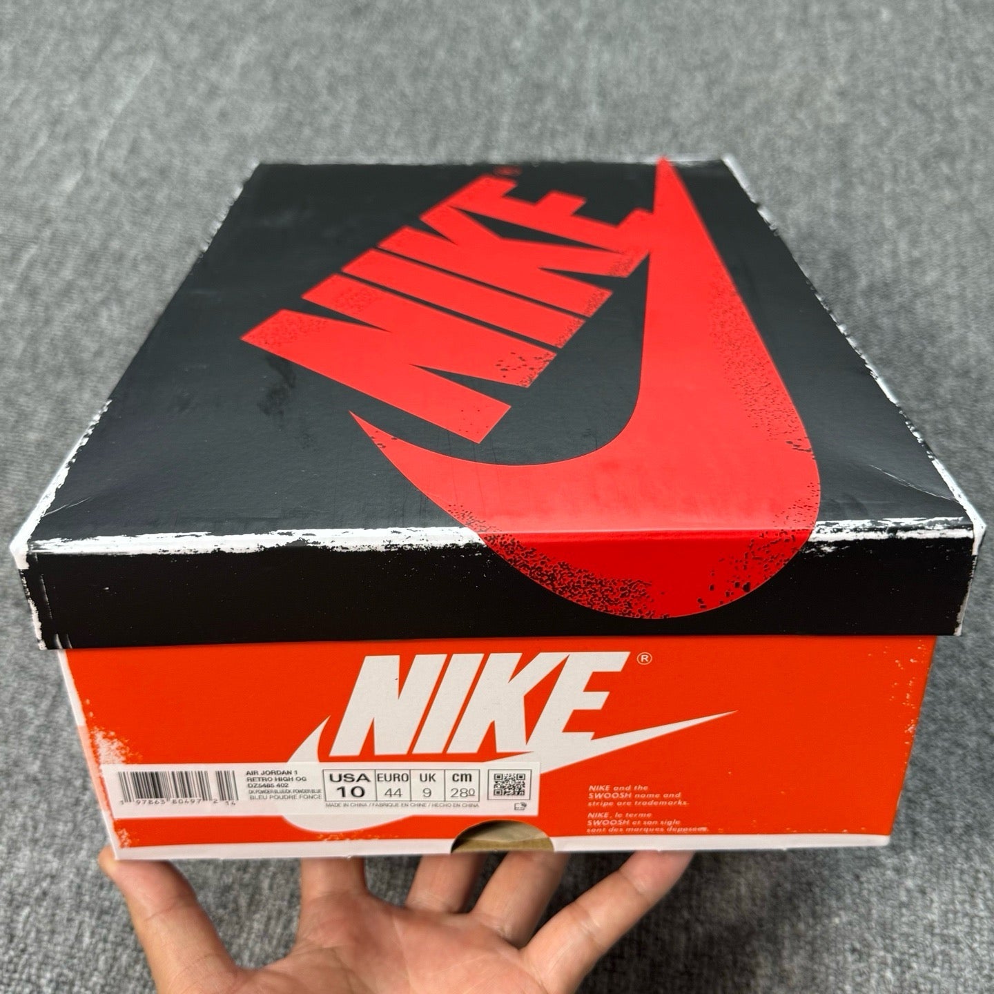 Shoe box with large Nike logo and orange-and-black design, size label visible