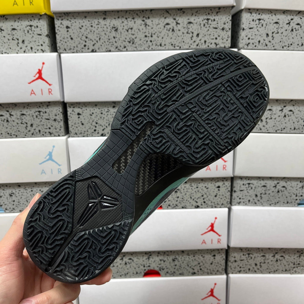 Black outsole of a basketball shoe with patterned traction tread and teal side edge.