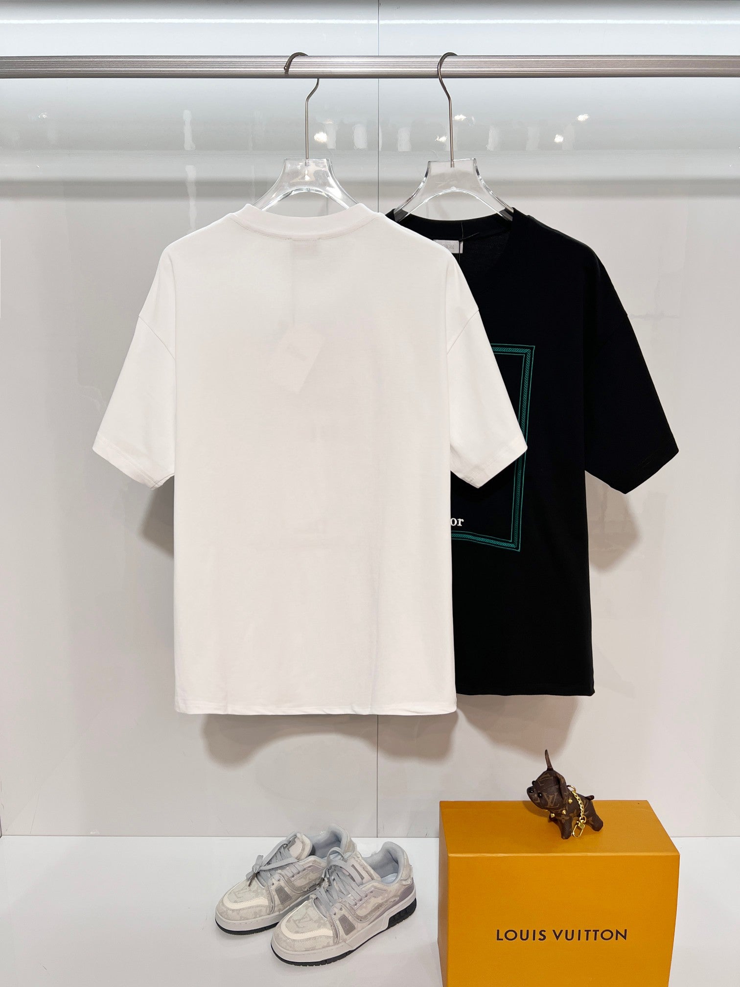 White Dior short-sleeve T-shirt with plain back and minimal branding; black shirt behind
