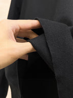 Black sweatshirt cuff detail with hand holding the sleeve
