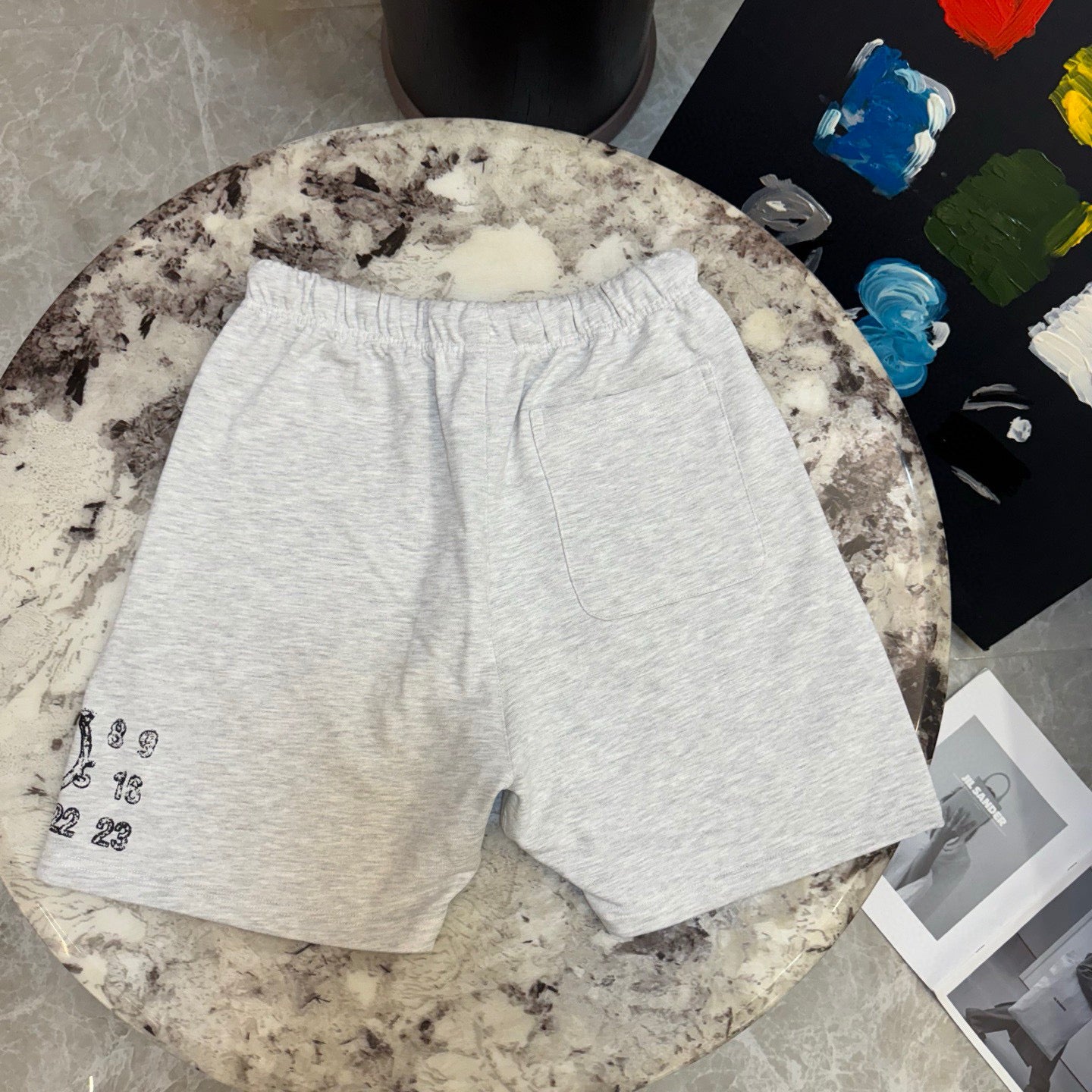 Light gray drawstring shorts with small number print on left leg