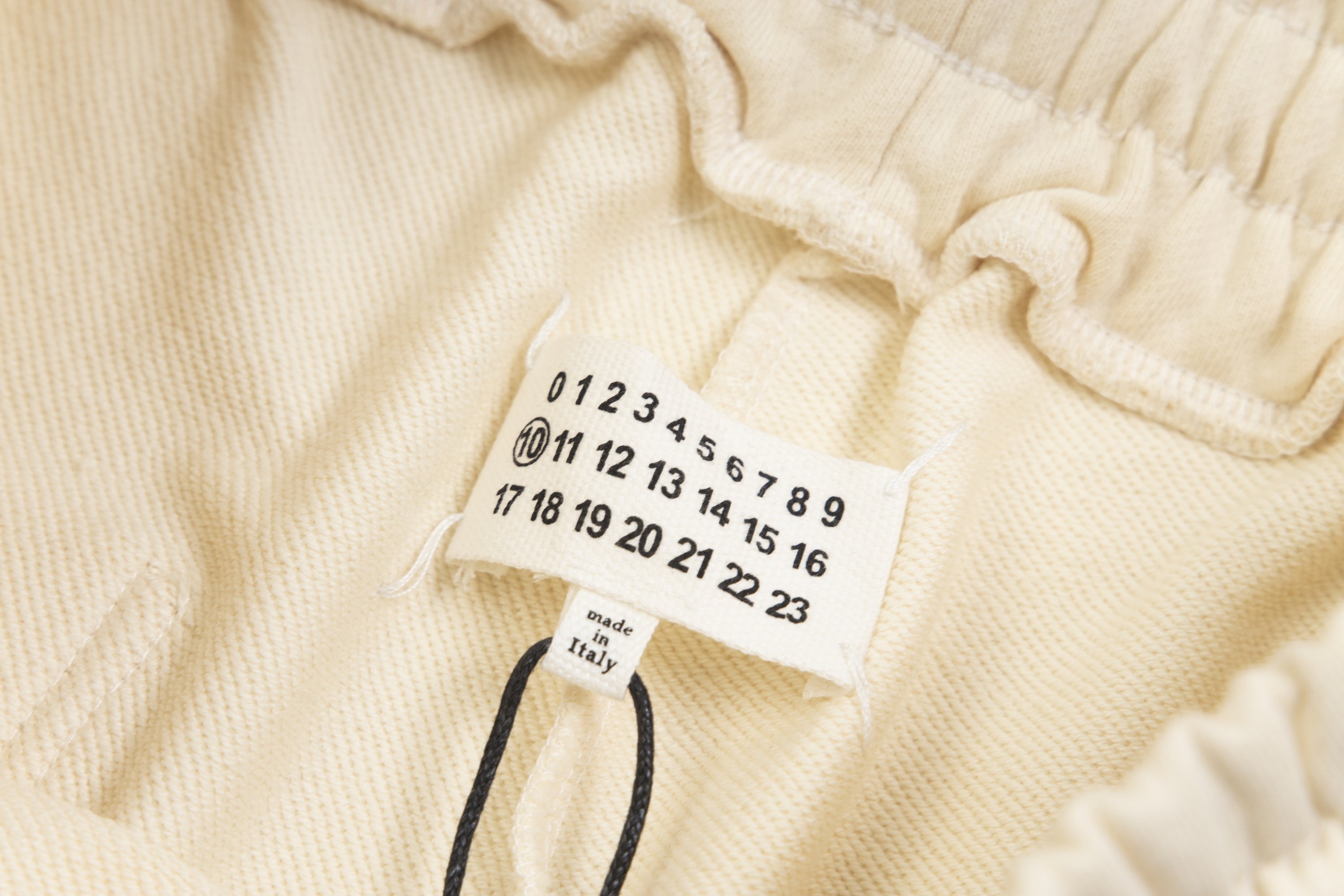 Beige Maison Margiela shorts care label with numbered size tags and drawstring cord.
