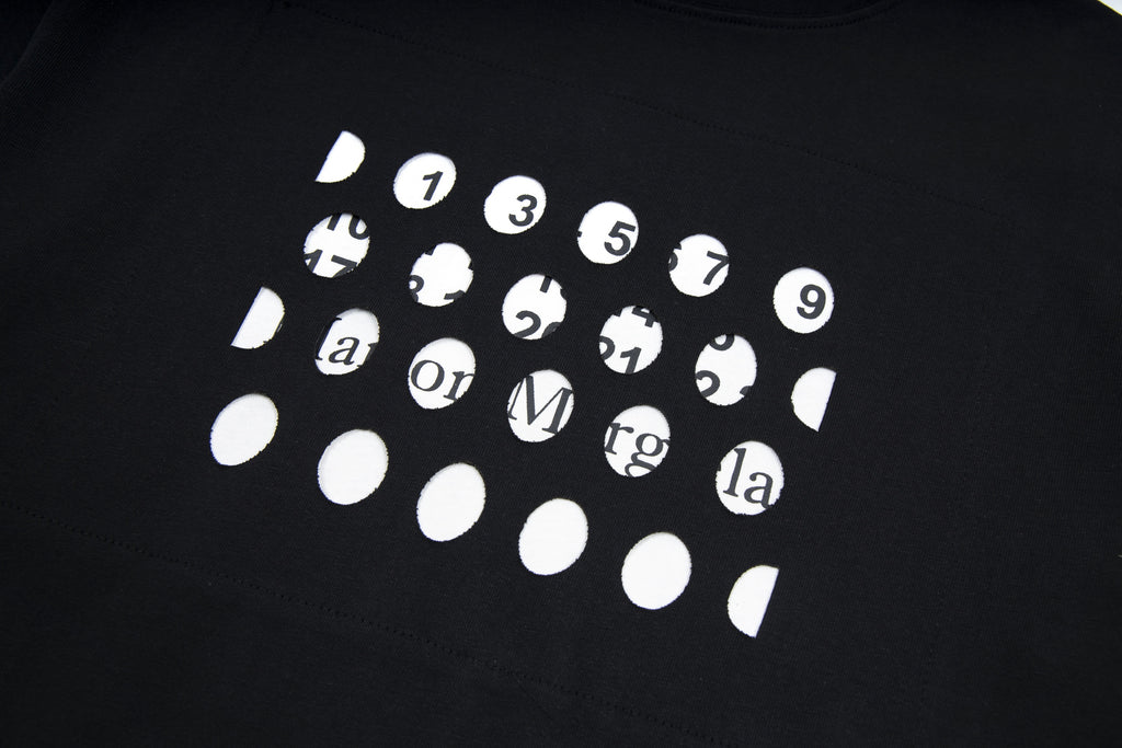 Black T-shirt with white graphic print of numbered faces and symbols