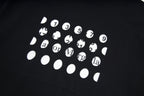 Black T-shirt with white graphic print of numbered faces and symbols