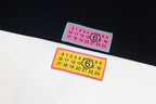 White T-shirt fabric close-up with two multicolor logo labels