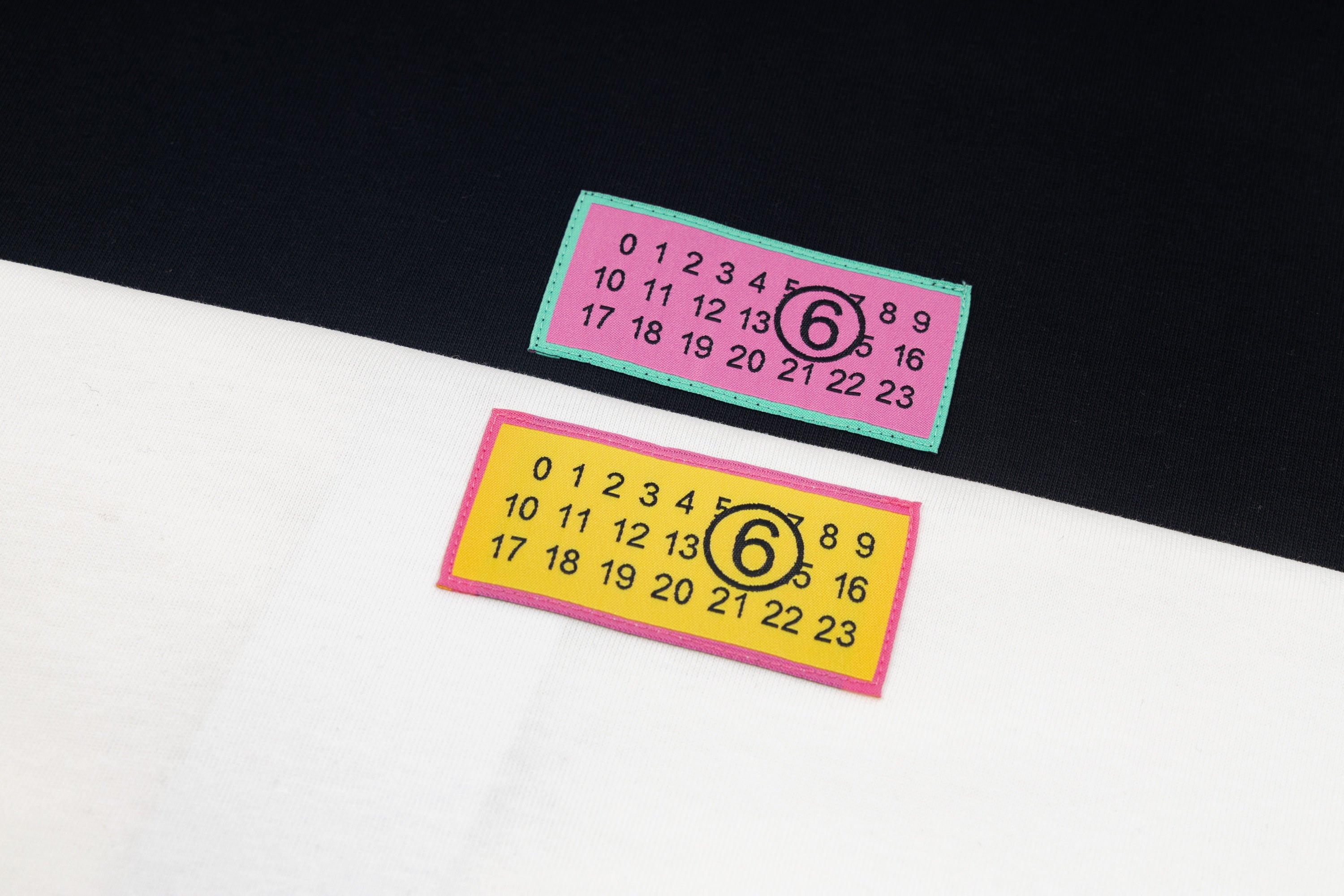 White T-shirt fabric close-up with two multicolor logo labels