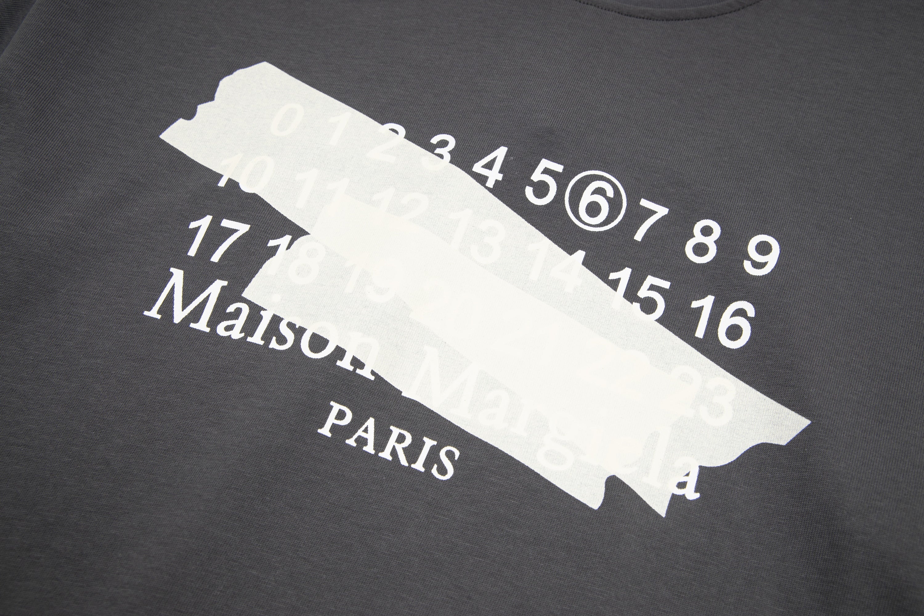 Black T-shirt front print close-up with number graphic and Maison Margiela Paris text
