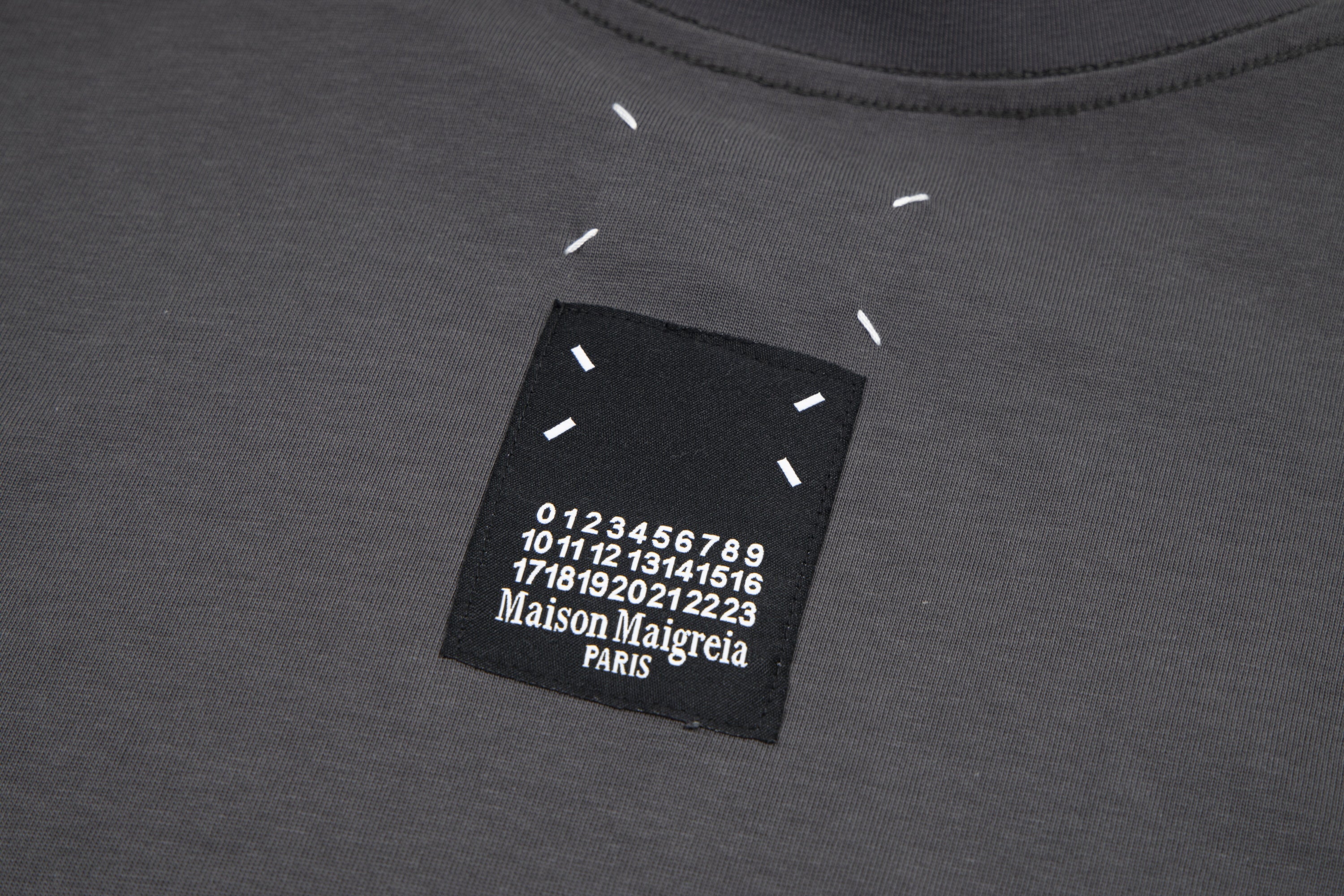 Black T-shirt neckline label with printed number graphic and Maison Margiela Paris text