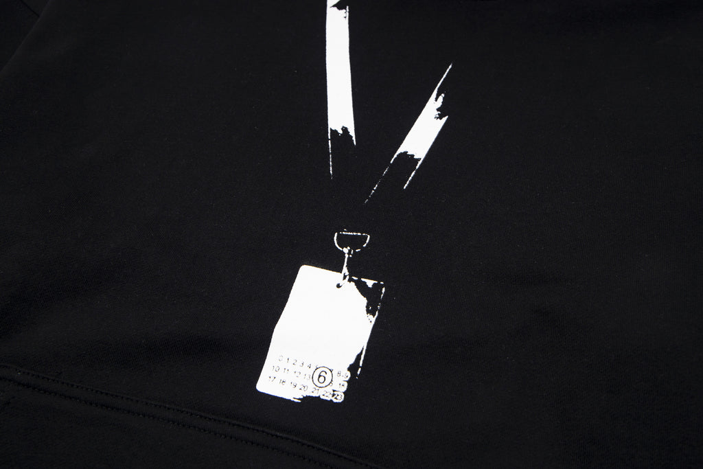 Black pullover hoodie close-up with drawstrings and brand hang tag on the chest