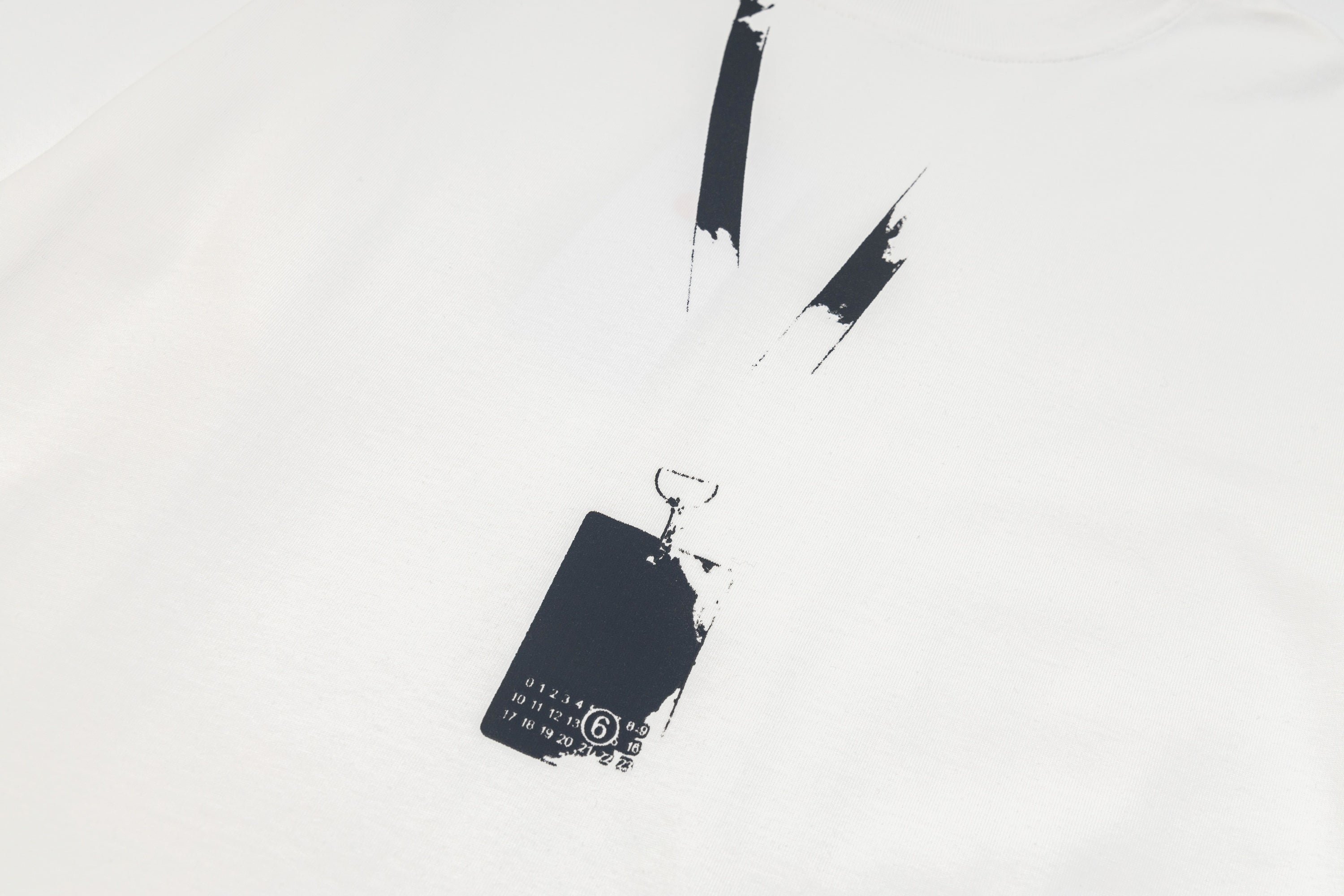 White long-sleeve T-shirt with black abstract logo print and hanging tag detail