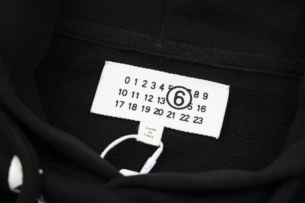 Black pullover hoodie interior with size label and care information tag near neckline