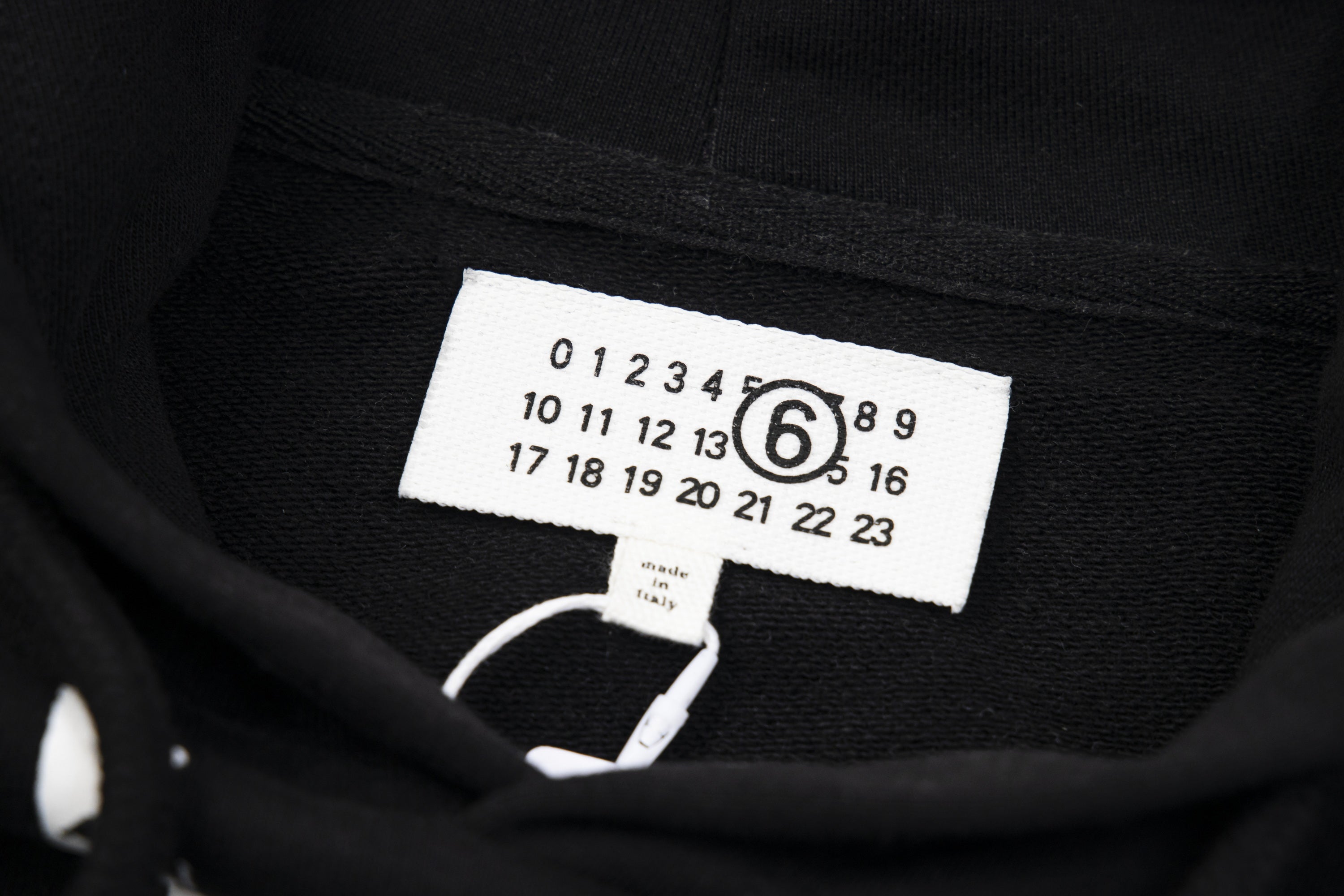 Black pullover hoodie interior with size label and care information tag near neckline