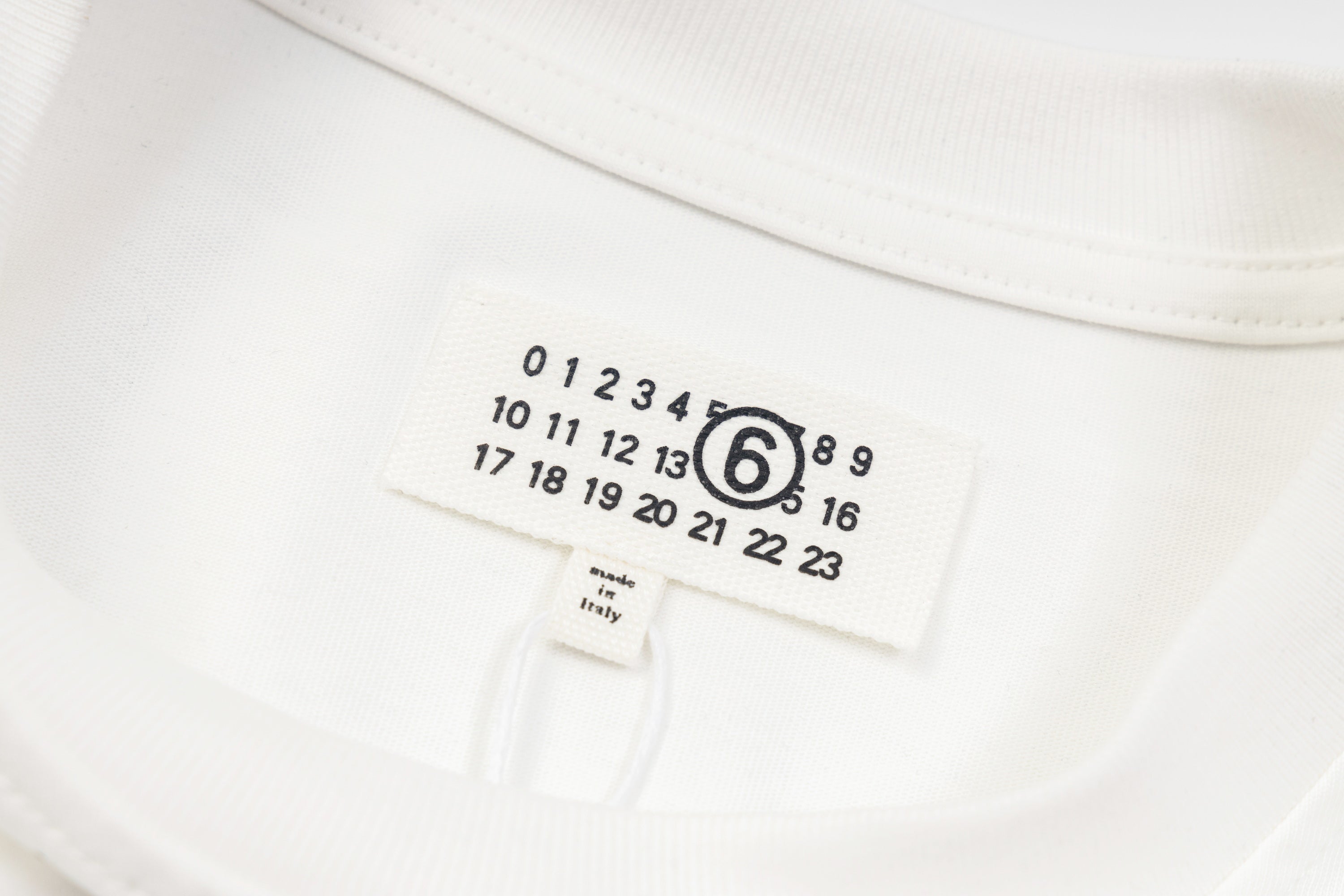 White long-sleeve T-shirt neckline label with size numbers and brand mark