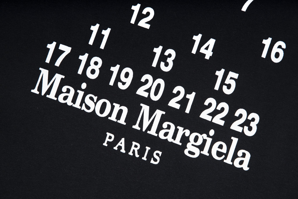 Black T-shirt close-up with large Maison Margiela PARIS text and numbers
