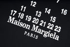 Black T-shirt close-up with large Maison Margiela PARIS text and numbers