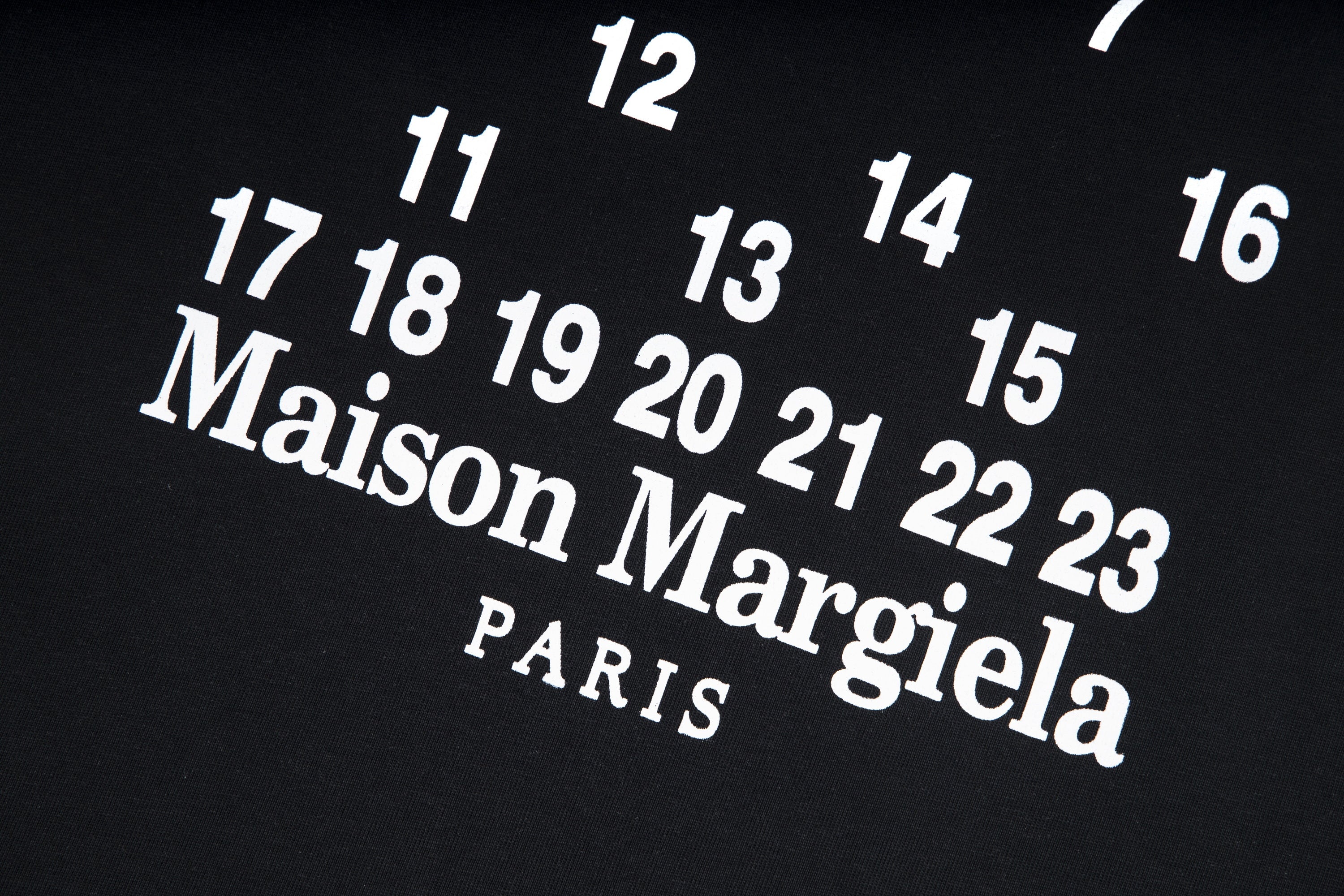 Black T-shirt close-up with large Maison Margiela PARIS text and numbers