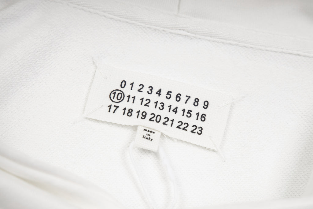 Maison Margiela fabric label with numbered scale, shown on white hood lining