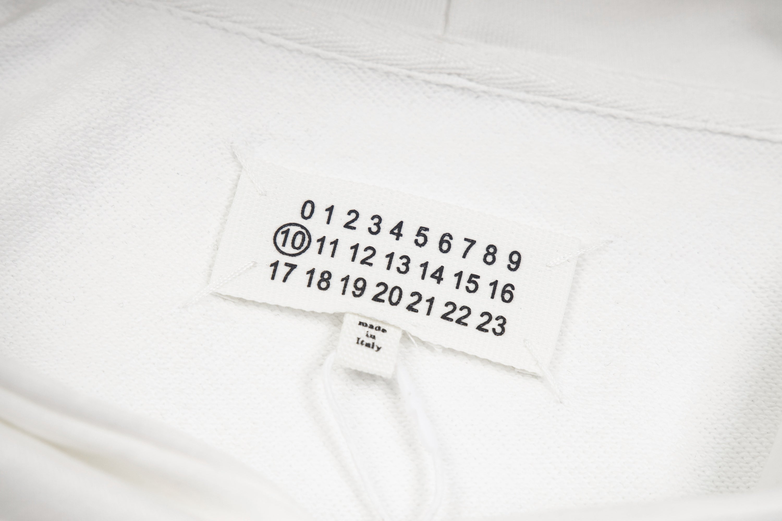Maison Margiela fabric label with numbered scale, shown on white hood lining
