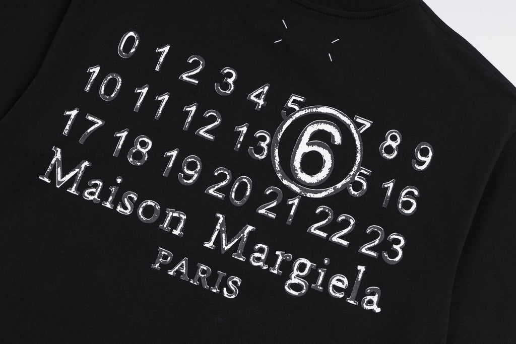 Black T-shirt close-up with circular “6” and “Maison Margiela Paris” print