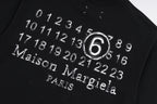 Black T-shirt close-up with circular “6” and “Maison Margiela Paris” print