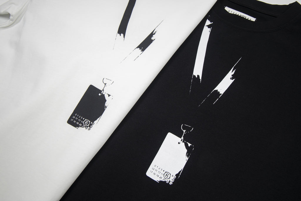 Close-up of black and white Maison Margiela T-shirts with abstract paint stripe print