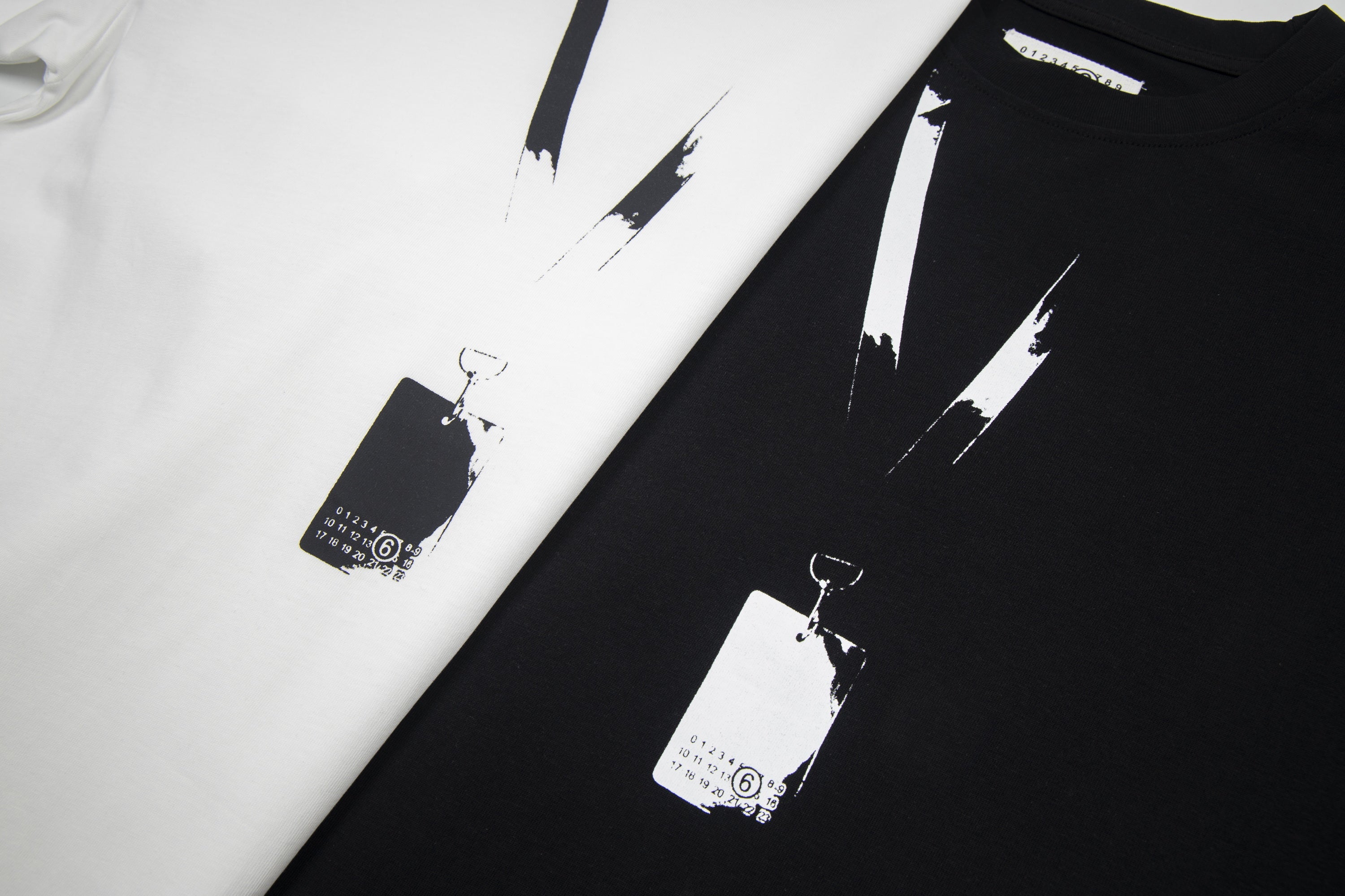 Close-up of black and white Maison Margiela T-shirts with abstract paint stripe print
