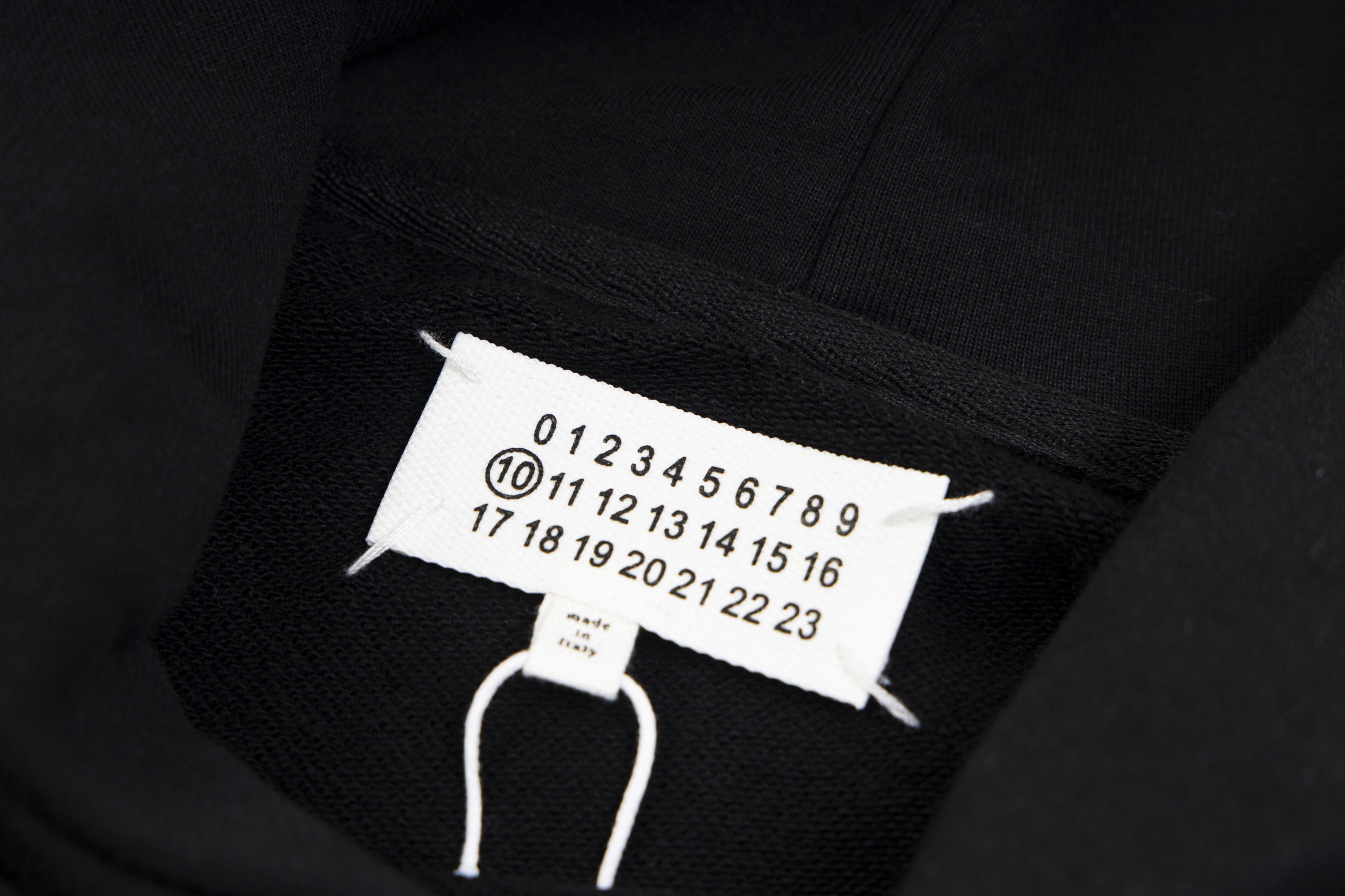 Black hoodie neck tag with size numbers and white drawstrings