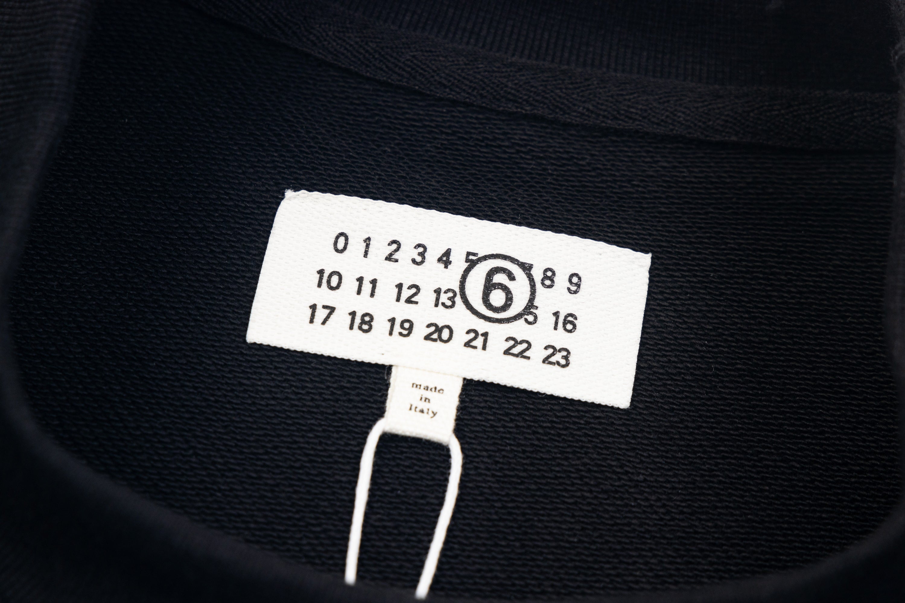 Black sweatshirt neckline label with '6' number graphic and size tag