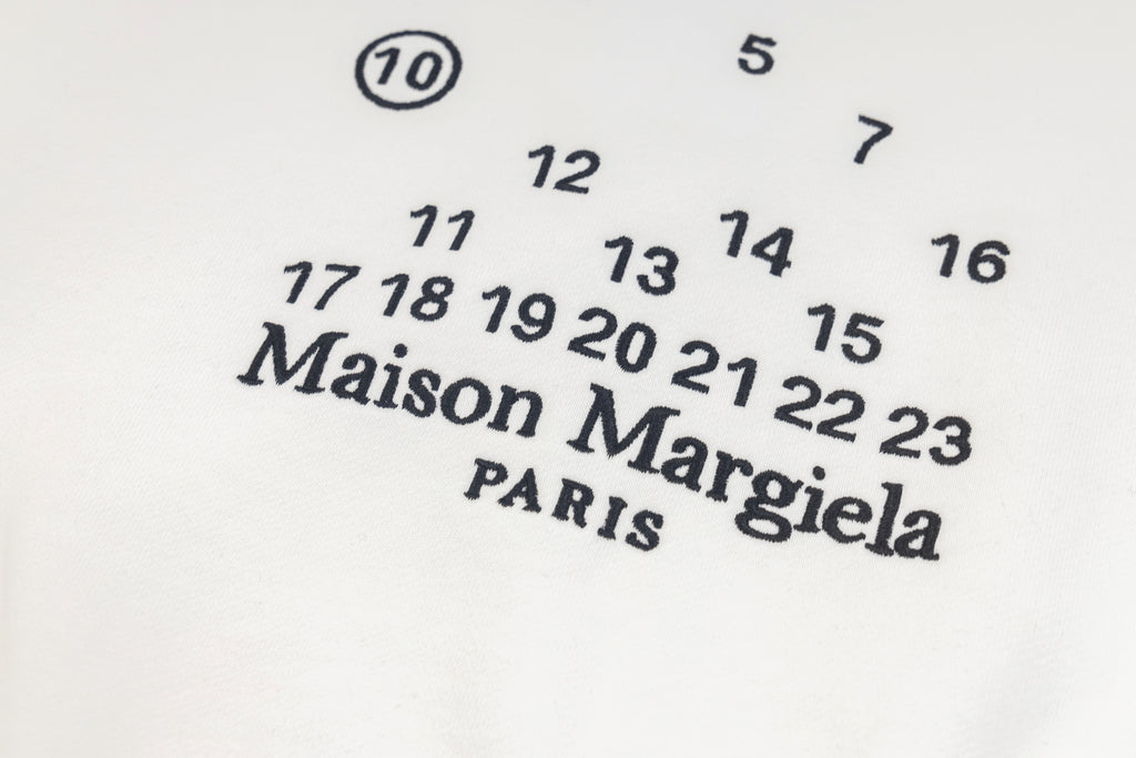 Close-up of Maison Margiela logo and numeric print on a white sweatshirt