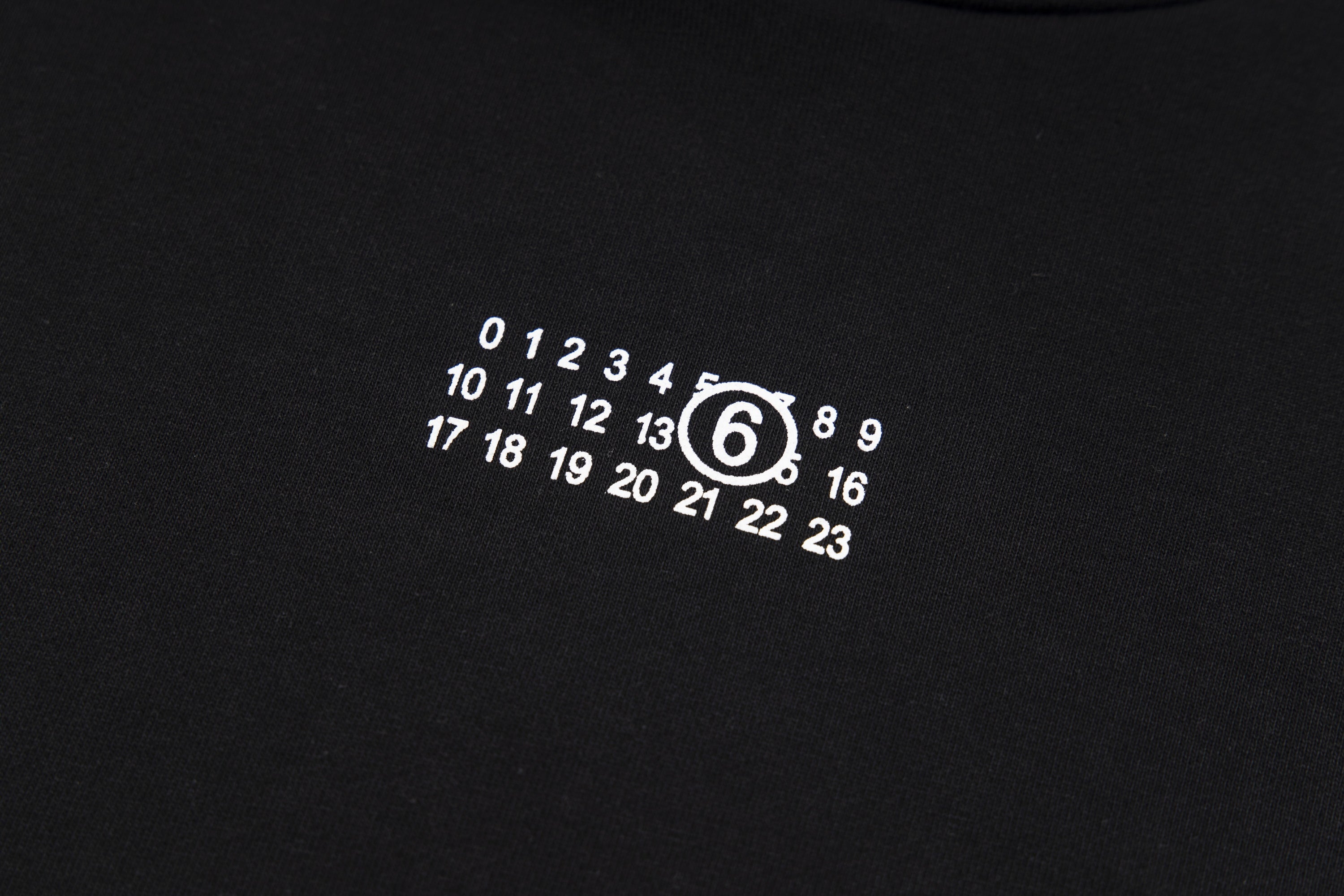 Black hoodie chest graphic with circular numeric logo print
