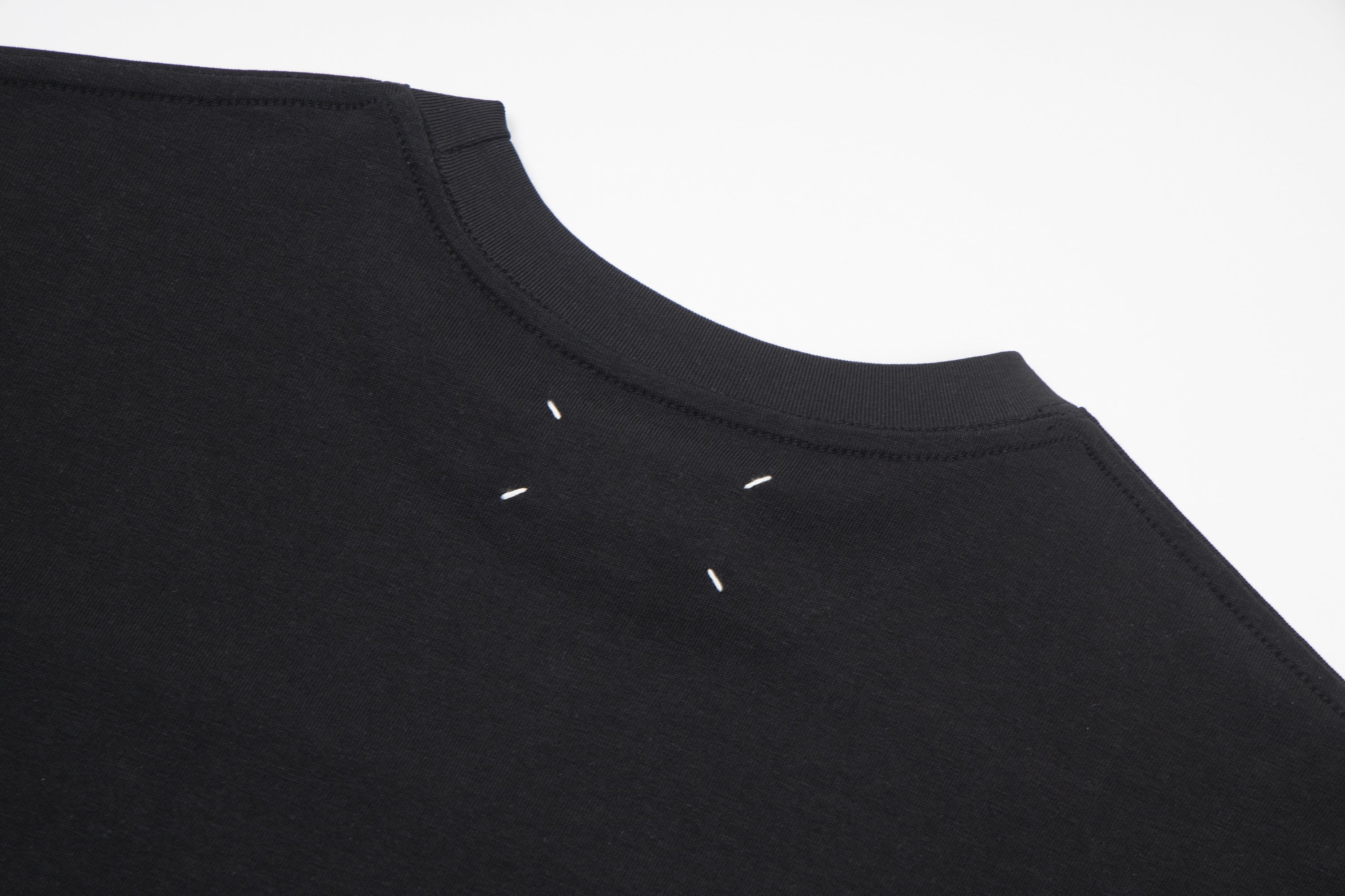 Black crewneck T-shirt with small decorative marks near neckline