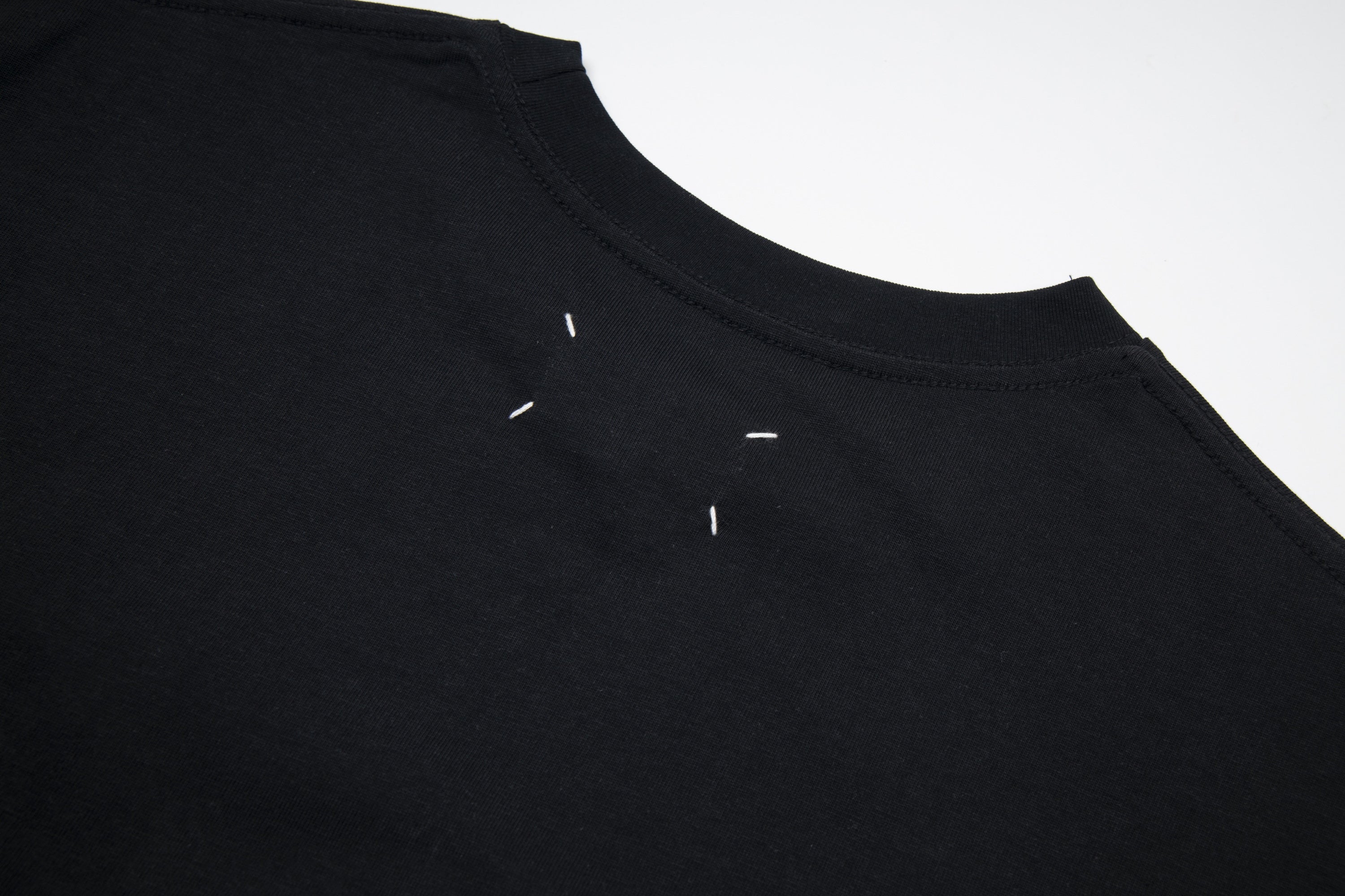 Black Maison Margiela T-shirt close-up of crew neck and small logo detail.
