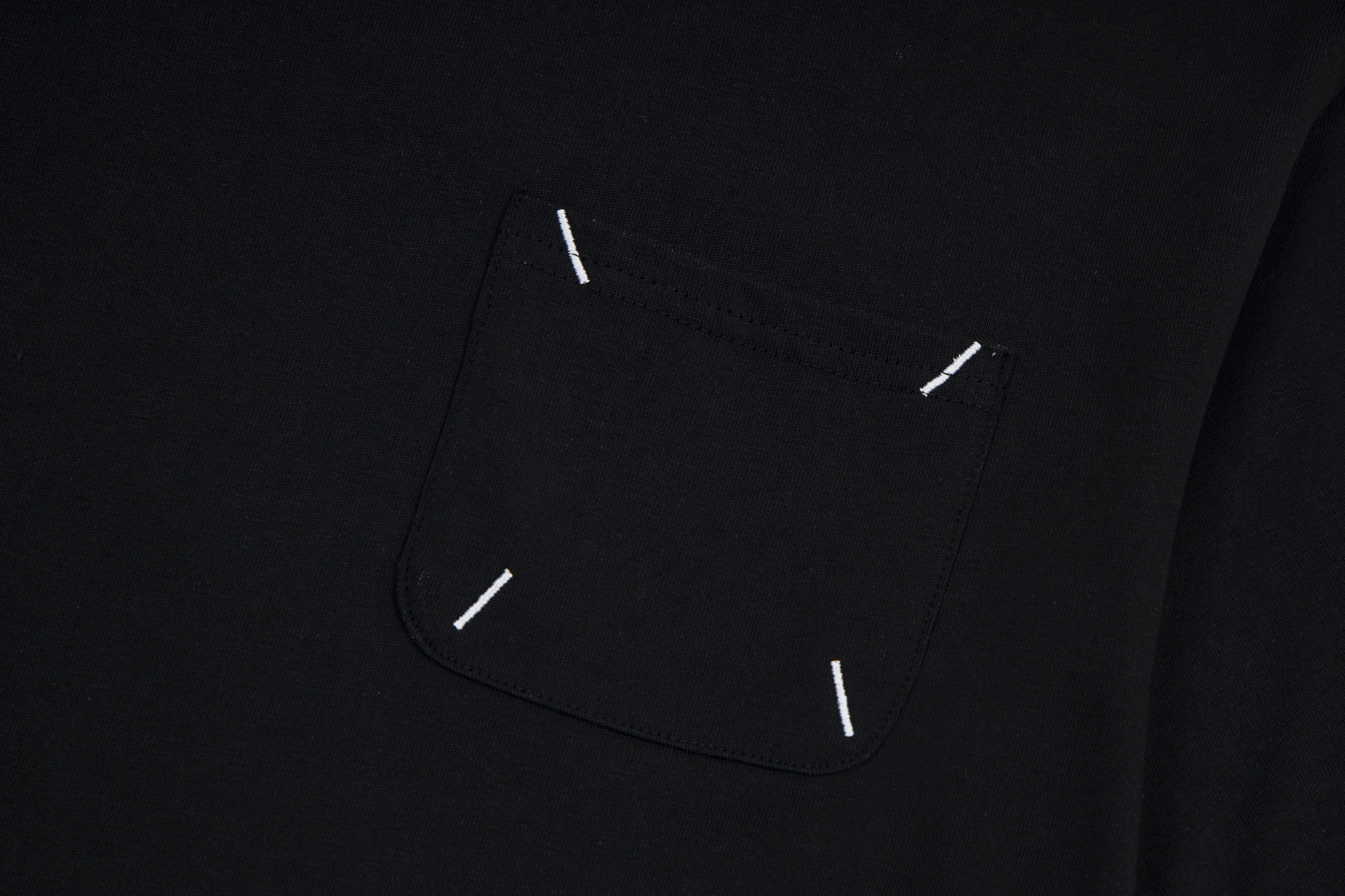 Black T-shirt chest pocket area with visible topstitch and small stitch details