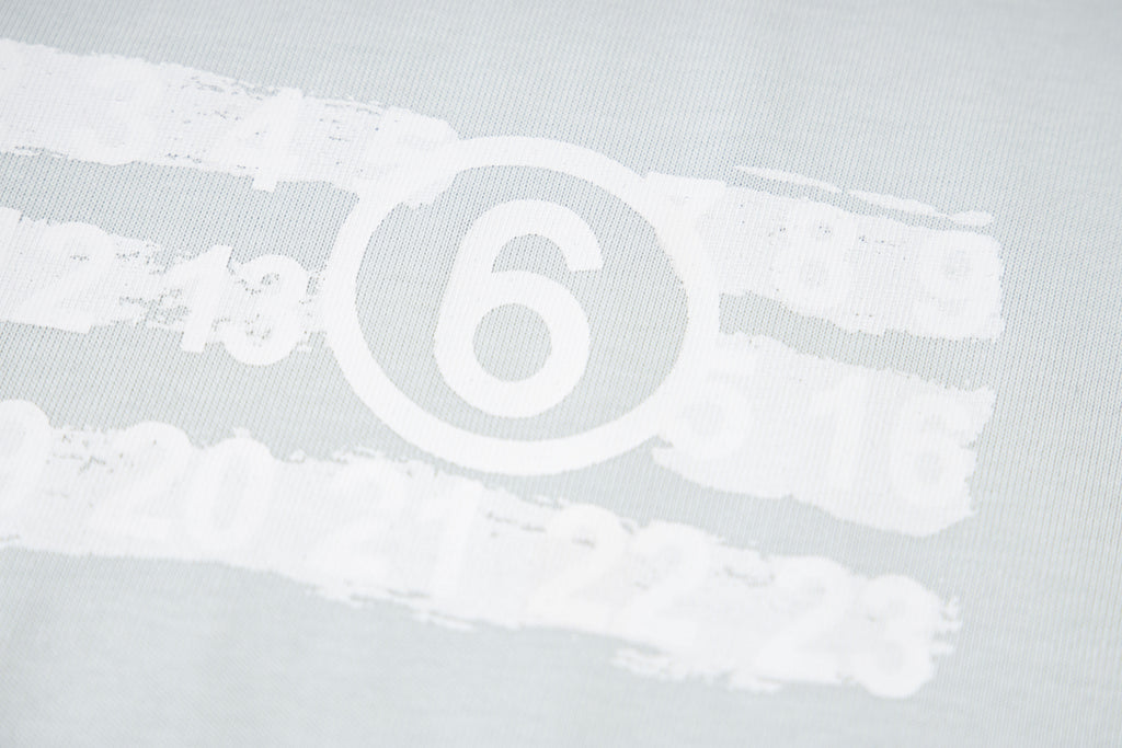Close-up of Maison Margiela '6' logo print on light fabric