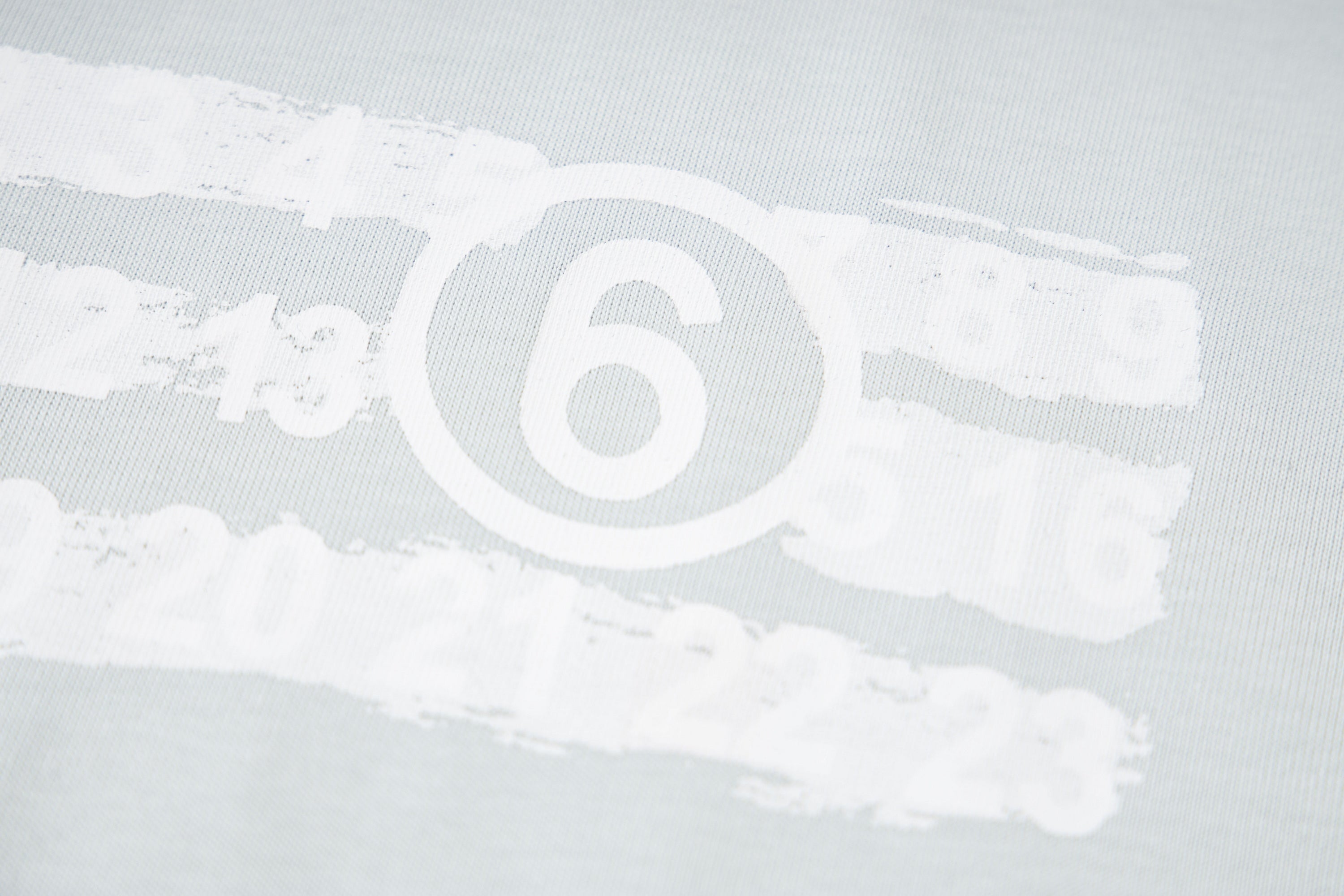Close-up of Maison Margiela '6' logo print on light fabric