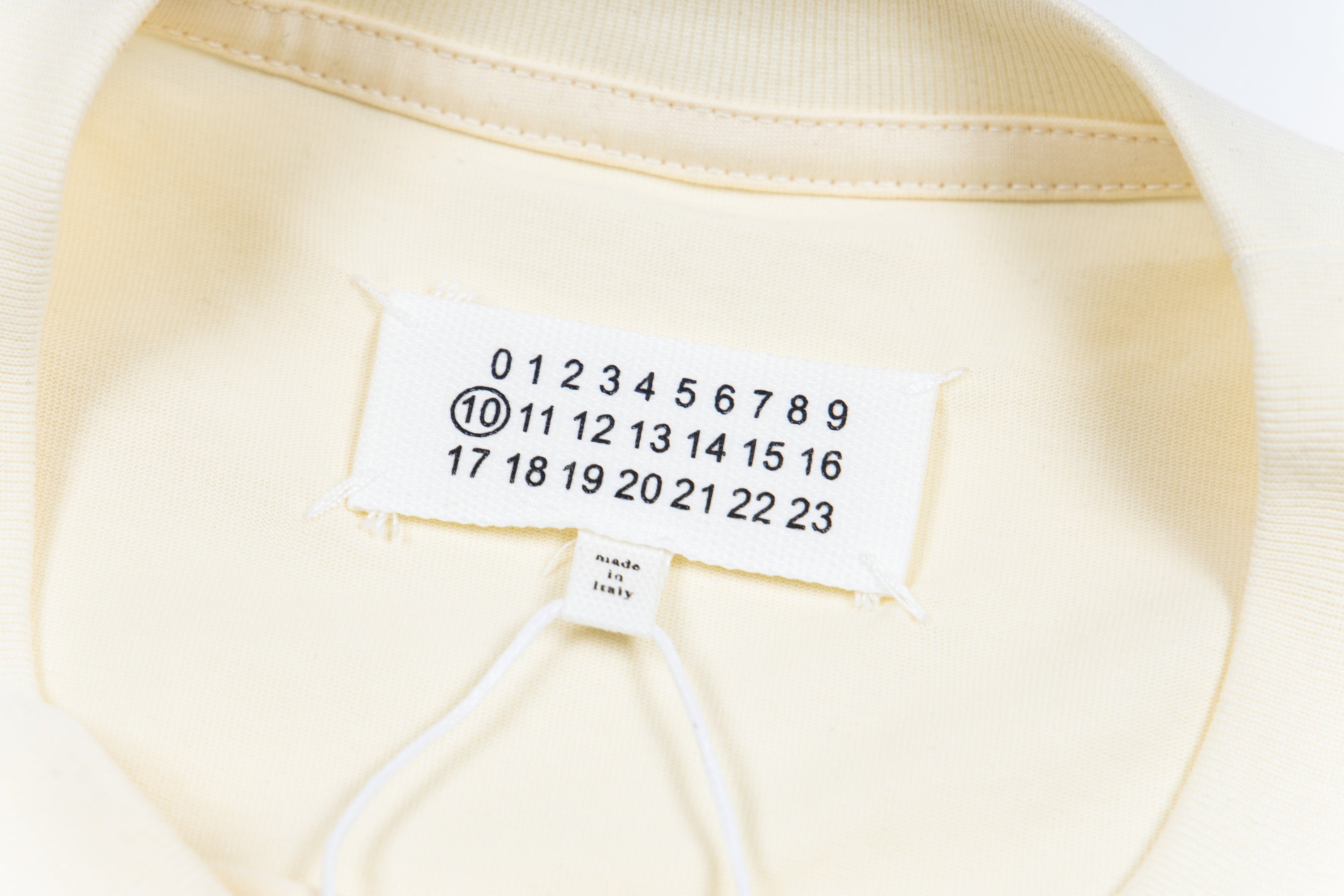 Cream T-shirt neckline and hem label with graphic number print