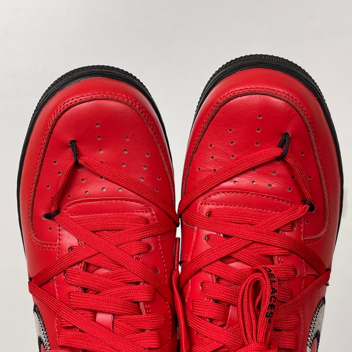 Red leather sneakers with red laces, perforated toe panels, black stitched sole