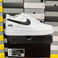 White low-top sneakers with black swoosh and Supreme label, laid-on side view