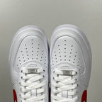White low-top sneakers with perforated toe box, white laces, red swoosh accents.