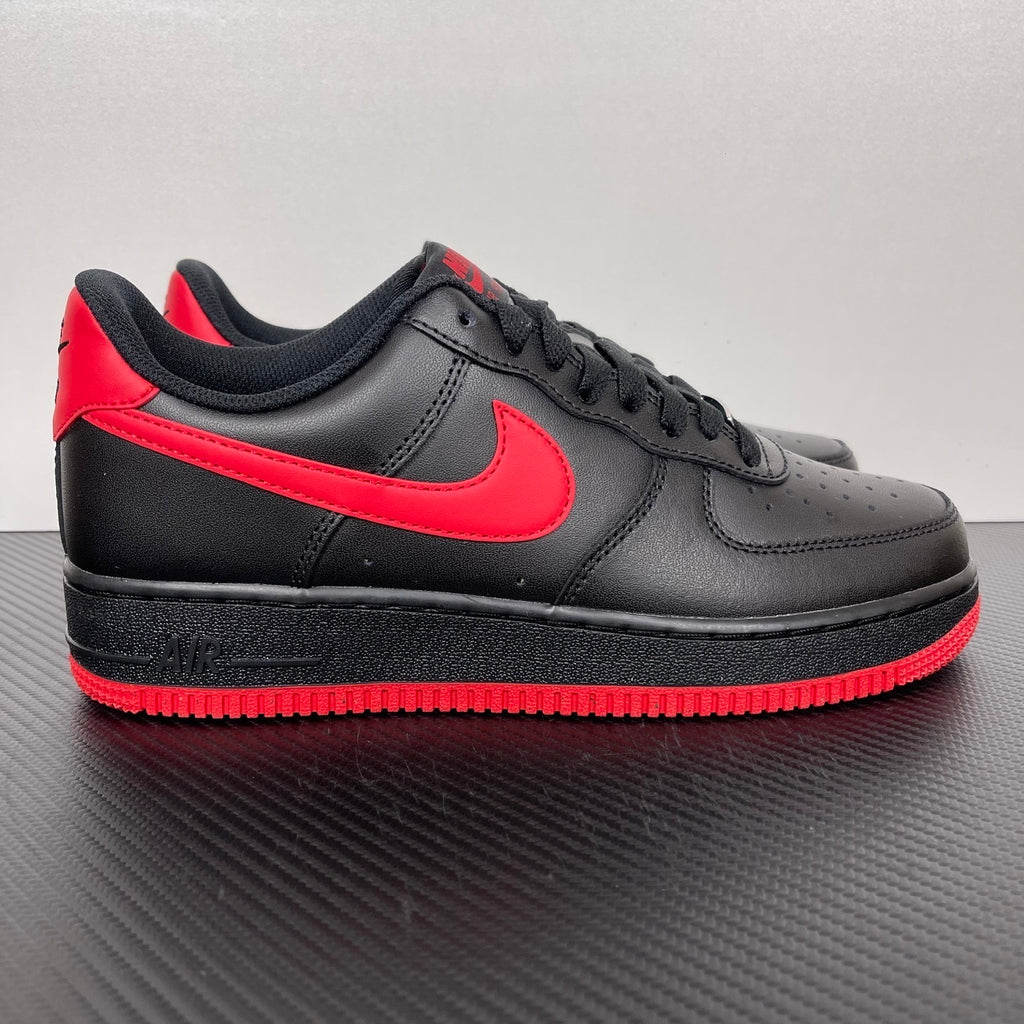 Black low-top sneaker with red swoosh and red-striped rubber sole
