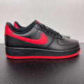 Black low-top sneaker with red swoosh and red-striped rubber sole