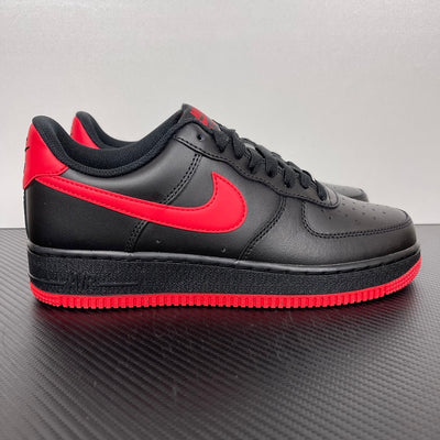 Black low-top sneaker with red swoosh and red-striped rubber sole