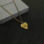 Gold heart pendant on a chain necklace, resting on its gift box.