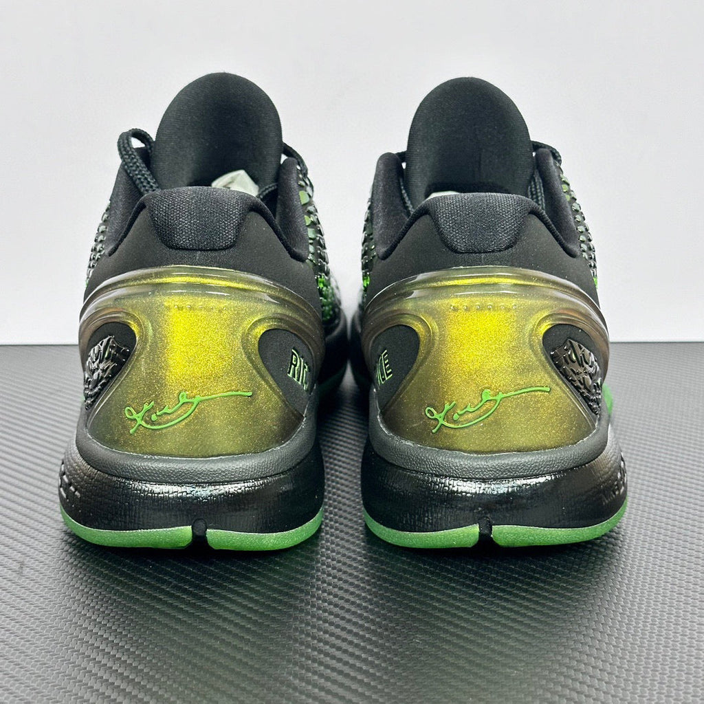 Pair of black and green basketball shoes, rear view with lime sole and ankle padding.