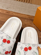 Pair of white cherry-print slide sandals, showing interior footbed text area