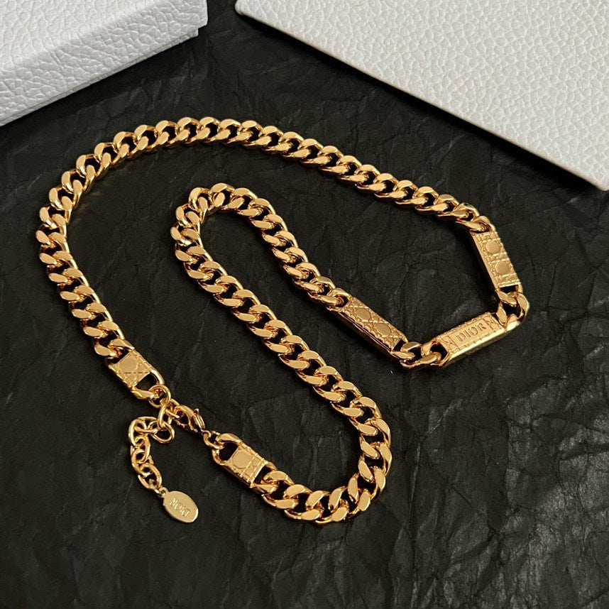 Gold chain necklace set with small hanging charm and rectangular logo tags